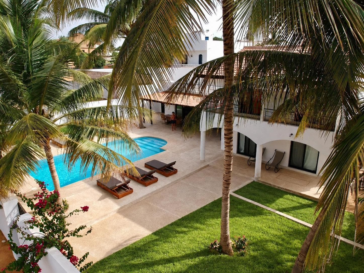 Villa blanche avec piscine, pelouse et cocotiers, vue depuis l'étage